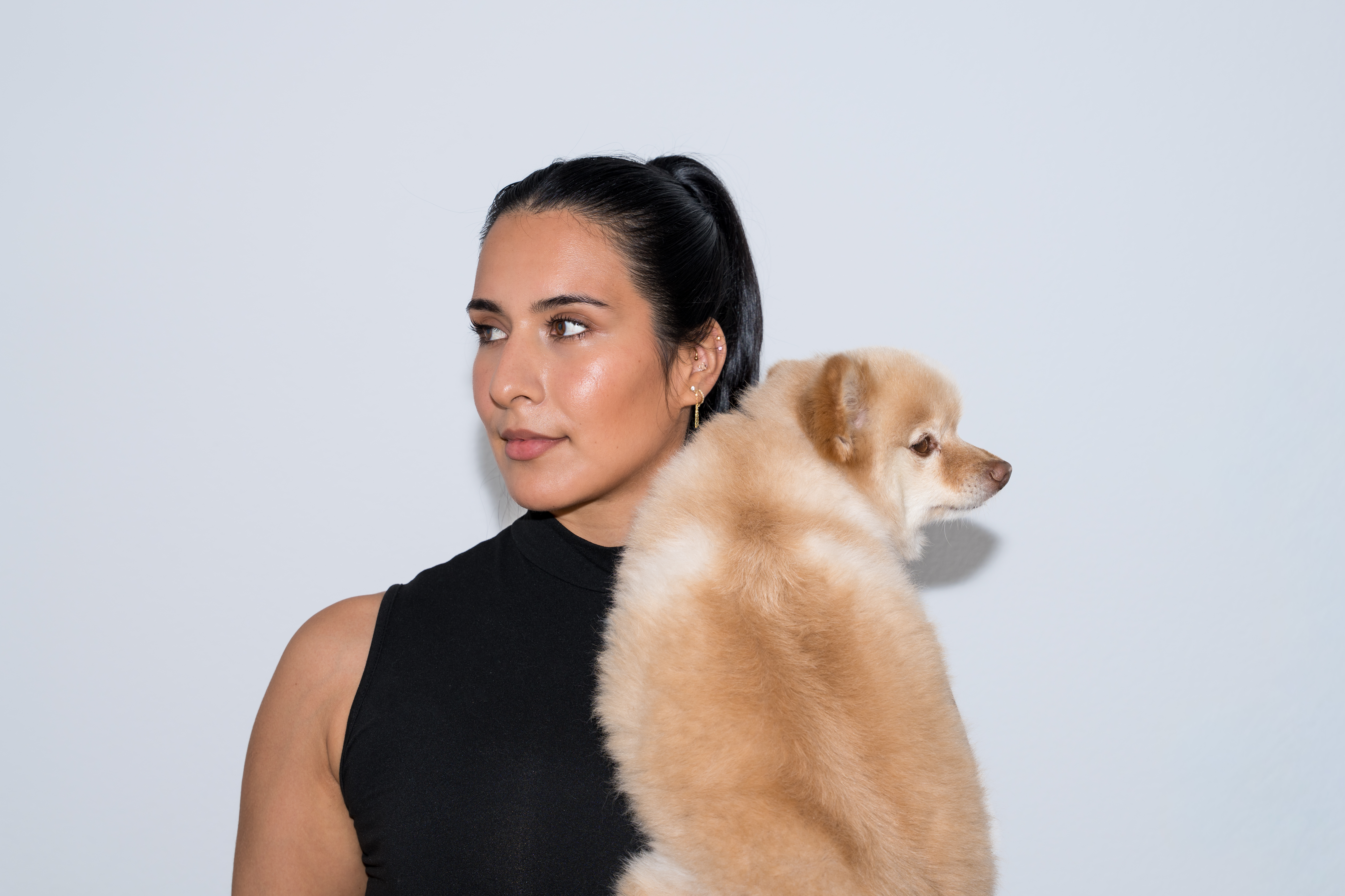 Studio headshot of a woman holding her small dog over one shoulder